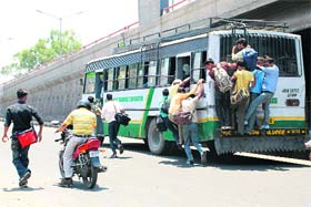 Passengers risk their lives while trying to board an overloaded bus in Jammu