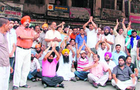 Shopkeepers of the old city area stage dharna after water entered their shops following rain on Tuesday morning.