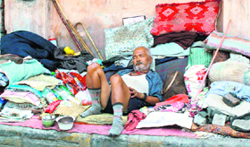 A beggar, in the midst of his belongings, enjoys a siesta on a pavement outside Doon Hospital in Dehradun.
