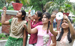 Girls watch the solar eclipse through CDs in Jalandhar on Wednesday.
