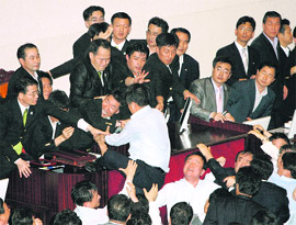 Security guards and the ruling Grand National Partys lawmakers block a vice-speaker of the National Assembly from passing controversial bills at the National Assembly main chamber, in Seoul on Wednesday