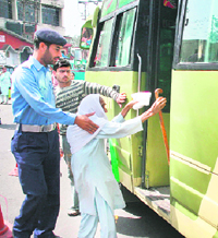 A traffic cop helps an old woman board a minibus in Jammu.