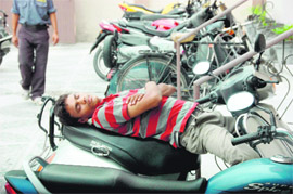 A young man enjoys a siesta on his scooter in Dehradun on Saturday.