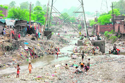 Slum children play on the dirty riverbed of the Bindaal in Dehradun. A Class II girl living in the vicinity was washed away in the river on Sunday night.