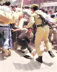 A protester scuffles with a policeman during a protest staged in Srinagar by temporary government employees on Monday, demanding permanent jobs
