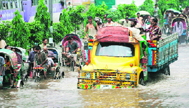 Rickshawpullers wade through knee-deep water alongside a truck on a street in Dhaka on Tuesday.