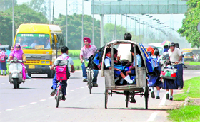 A rickshaw-puller carries school kids through wrong side on a busy road near the Sector 43 ISBT in Chandigarh.