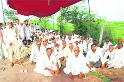 Members of the Kadyan Barah khap panchayat stage a dharna outside Dharana village in Jhajjar on Thursday.