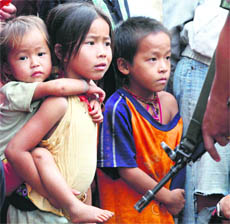 Hmong hilltribe refugee children stand in front of a guard at Ban Huay Nam Khao camp in Phetchabun province, about 416 km north-east of Bangkok, on Thursday.