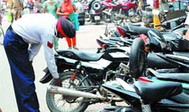 A traffic policeman removes air from the tyres of a motorcycle parked outside the line in Amritsar.