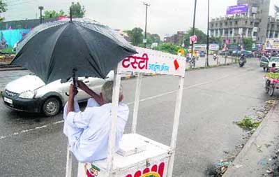An ice-cream seller takes cover from rain in Dehradun 