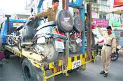 A policeman tows away two-wheelers of underage drivers in Dehradun