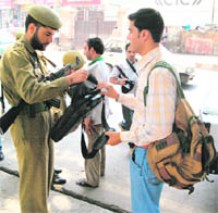A policeman searches the bag of a youth in Srinagar on Monday. Security has been tightened in the summer capital in view of the coming Independence Day. 