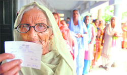 An elderly woman shows her ID card while standing in a queue at a polling station in Lalru. 