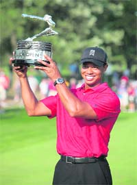 Tiger Woods holds up the trophy after winning the Buick Open golf tournament