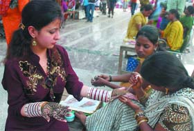 A woman gets henna applied on her palms for Raksha Bandhan at Hanuman Mandir in New Delhi