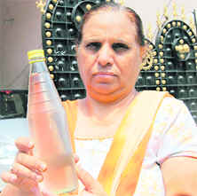 A woman shows contaminated water in a bottle on Tuesday