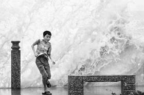 A boy plays in front of waves triggered by tropical storm Goni along the shores of Sanya in China