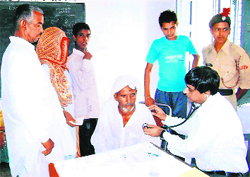 A doctor examines a patient at a medical camp organised by the police in Shiekhpura Khalsa village in Karnal on Sunday.