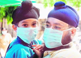 A father-son duo wear protective masks as they wait for their turn for an H1N1 test outside a special screening centre at Ram Manohar Lohia Hospital in New Delhi