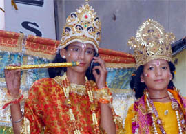 A kid dressed as Krishna attends a call on his mobile phone during the Janmashtami procession in Jalandhar on Tuesday.