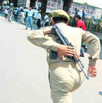 A policeman chases government employees during a protest in Srinagar on Wednesday.