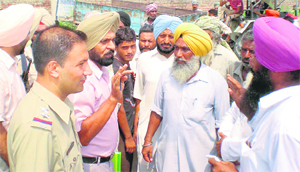 SHO Naveenpal Singh and XEN Gurmeet Singh persuade farmers following a protest at the PSEB power grid, Jagraon, on Wednesday