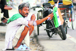 Right to work: A man awaits buyers as he holds national flags on the eve of Independence Day in Ludhiana on Friday.