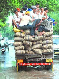 Two hoots to norms: Unmindful of the risk involved, youth cling to the ropes of an overloaded truck in Mohali