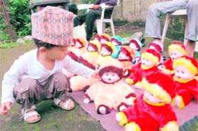 A Gorkha boy checks out dolls at a makeshift market on the occasion of Haryali Teej celebrated by the Gorkha community in Dehradun