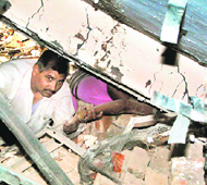 A man tries to rescue a woman trapped inside the debris of a collapsed building in Sector 15, Faridabad, on Sunday.