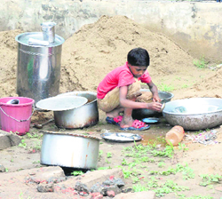 A child washes utensils at a roadside dhaba near Karna Park in Karnal on Sunday.