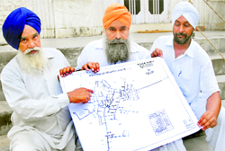 Gurmeet Singh (centre) shows the map of Kanech village near Doraha in Ludhiana.