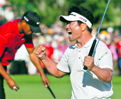 Yang Yong-eun (R) of South Korea celebrates his victory as Tiger Woods looks away during the final round of the PGA Championship golf tournament at Hazeltine National Golf Club in Chaska, Minnesota on Sunday.