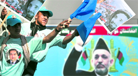 Afghan President Hamid Karzai is seen pictured on a billboard in the backgrond as supporters of presidential candidate Abdullah Abdullah wave his posters during a campaign rally in National Stadium in Kabul on Monday.