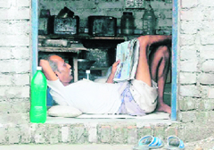 A shopkeeper reads a newspaper leisurely in Dehradun on Tuesday.