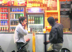A youth pours beer in a glass at a liquor vend in Sarabha Nagar.