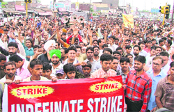 Agitating industrial workers hold protest at Samrala Chowk on Wednesday. 