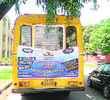 A school bus carrying an advertisement on its rear.