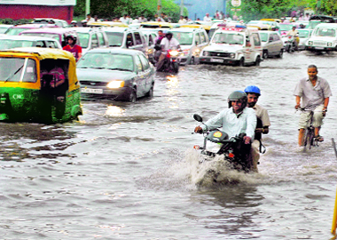 Commuters are seen on a flooded road during a sudden downpour in New Delhi on Friday.