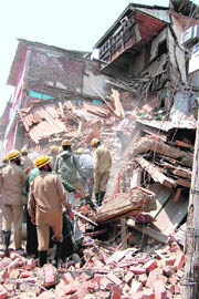 Fire staff and cops take part in a rescue operation after a wall of Hotel Coronation collapses in Srinagar on Friday.