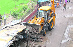 A JCB machine removes shanties during an anti-encroachment drive in Ludhiana on Friday.