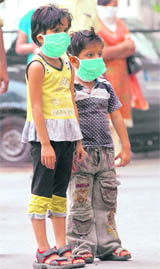 Children wear protective masks as they wait to undergo H1N1 virus test at Ram Manohar Lohia Hospital in New Delhi on Friday