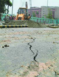 Workers on Saturday repair a section of road near the Press Club of India in New Delhi that caved in during Fridays downpour, creating a 10-metre-deep hole