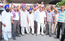 Members of the Ludhiana Auto Rickshaw Association raise slogans against the DTO near the Clock Tower in Ludhiana 