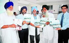 AS Sekhon and Kamaljit Singh, principal and chief executive officer of Gian Sagar Medical College and Hospital, respectively, release a souvenir at the launch of a health insurance scheme at Patiala.