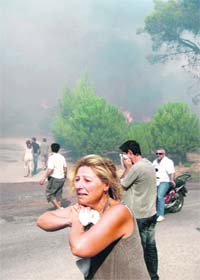 A woman cries for help as a forest fire closes in on her home in the Anthousa suburb, north of Athens