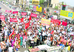 Railway employees and activists of labour unions take out a protest march and block the traffic at Jagraon Bridge in Ludhiana on Wednesday.