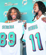 Serena (L), and Venus Williams pose while displaying their Miami Dolphins jerseys after it was announced the tennis stars had become minority owners of the NFL football team, in Davie, on Tuesday.