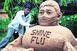 An artist creates a sand sculpture to raise awareness on swine flu in Bhubaneswar on Saturday.
